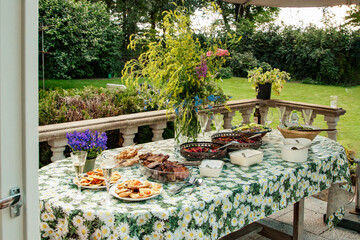 Festive buffet table with vegetarian dishes at a party in the garden. Outdoor ceremony with catering. Buffet with delicacies, decorated with wildflowers for an outdoor ceremony