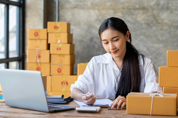 Young Asian business woman startup sme small business entrepreneur SME distribution warehouse with parcel mail box. SME Online marketing and product packaging and delivery service.