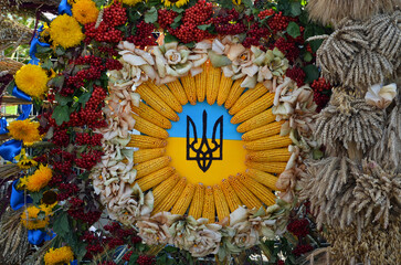 coat of arms and flag of Ukraine surrounded by flowers, ears of corn and viburnum