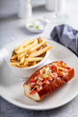 Lobster roll with fries on a plate topped with green onions
