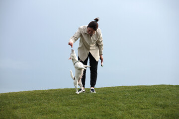 Girl gives tasty patches of dog treats to a white dog on the background of the sky