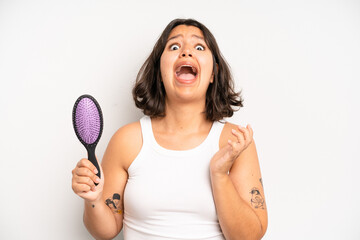 hispanic pretty girl screaming with hands up in the air. hair comb concept
