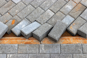 Pavement repairs and paving slabs laying on the prepared surface, with tile cubes in the background. Laying paving slabs in the pedestrian zone of the city. Paving slabs and curbs.