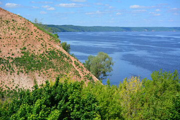 steep slope of mountain with dark blue river on the horizon