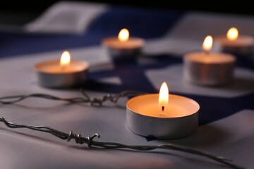 Burning candles and barbed wire on flag of Israel. Holocaust memory day