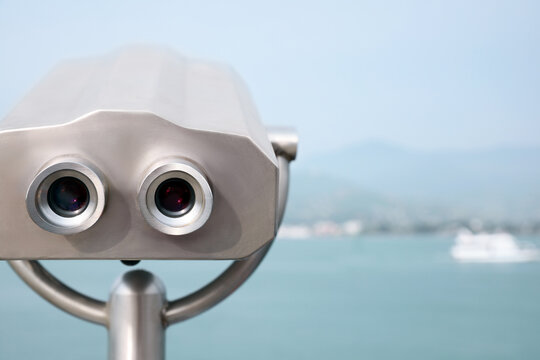 Metal tower viewer installed near sea, space for text. Mounted binoculars