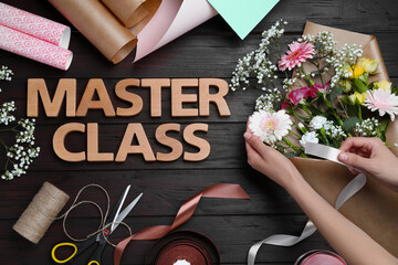 Woman arranging flowers at wooden table with supplies and words Master Class, top view