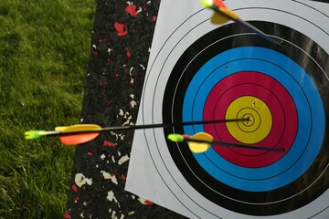 Arrows in archery target on green grass outdoors, closeup