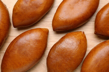 Many delicious baked patties on parchment paper, flat lay