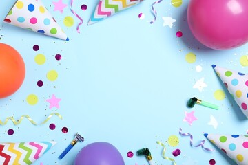 Frame made of party hats and birthday decor on light blue background, flat lay. Space for text.