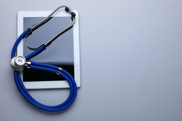 Medical stethoscope and tablet on white background, top view. Space for text