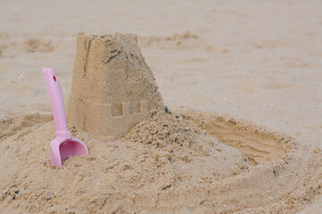Fototapeta na wymiar Beautiful sand castle and plastic toy on beach, space for text