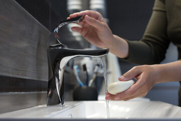 Woman with soap bar washing hands in bathroom, closeup