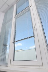 Window with horizontal blinds indoors, low angle view