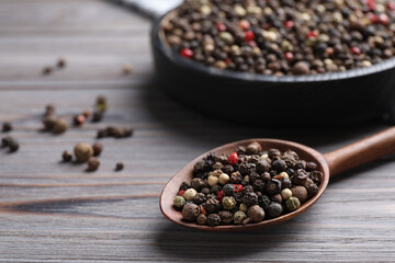 Different peppercorns on light grey wooden table, closeup