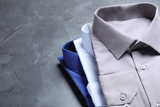 Stylish shirts on grey stone table, space for text. Dry-cleaning service