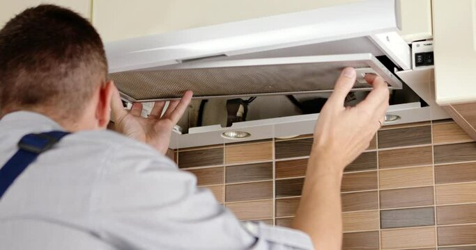 repairman cleaning a kitchen hood air filter