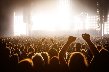 A lot of people raised up hands at the concert event. Fans arms against the stage light.