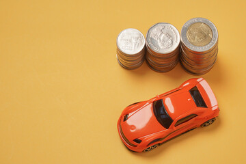 Car model with coins. Leasing and insurance concept on yellow background. Finance, Loan, Saving money with copy space.