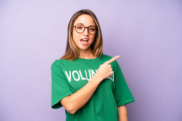 pretty caucasian woman looking excited and surprised pointing to the side. volunteer concept