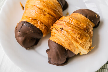 Crispy croissants on the bed. French breakfast. Fresh bakery. Croissants in chocolate on a plate.
