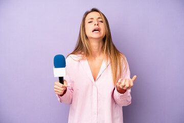 pretty caucasian woman looking desperate, frustrated and stressed. journalist and microphone concept