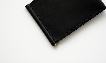 Black men's money clip handmade leather wallet for cards lies on a white table. Leather goods and accessory.