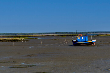 colorful boat resting on the mud at low tide near Setubal, Portugal