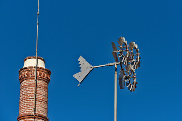 Obraz premium disused factory chimney and metal weather vane, in Setubal, Portugal