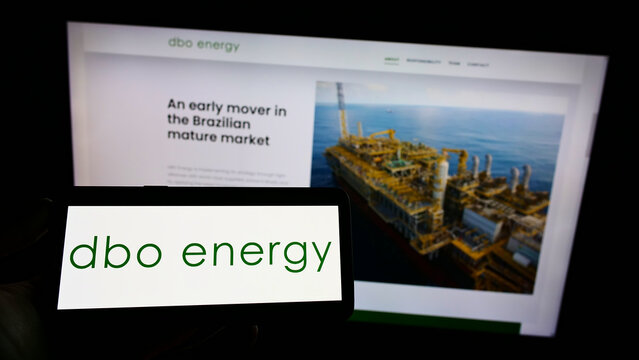 Stuttgart, Germany - 01-08-2022: Person holding smartphone with logo of Brazilian oil and gas company DBO Energy SA on screen in front of website. Focus on phone display.
