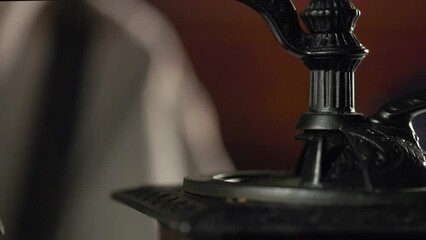 Close up of a small amount of coffee beans being poured into a vintage grinder from the pan of a balance scale.