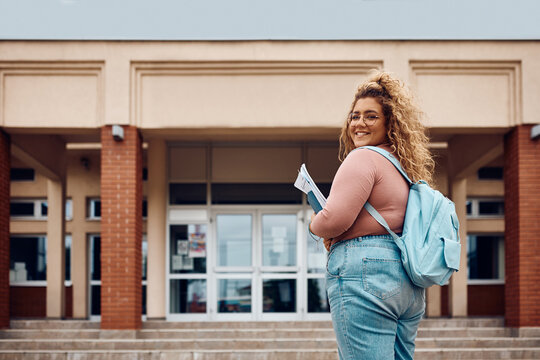 Happy college student going on lecture and looking at camera.