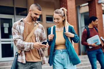 Happy university students using cell phone at campus.