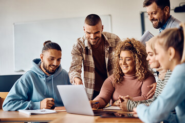 Happy college students and their teacher using computer in classroom.