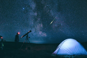 Amateur astronomer with astronomical telescope camping in nature under the Milky way stars. - obrazy, fototapety, plakaty