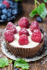 Berry tartlet with cream on a black background. Summer fruit baking. Tartlet with raspberries, blueberries Top view