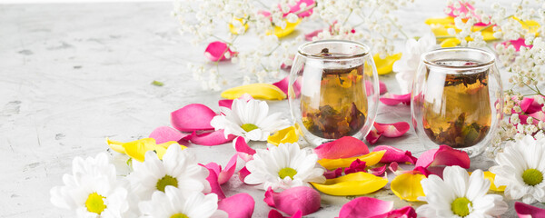 Creative layout of a cup of tea, green tea, decorated fresh flowers on a grey background. Banner