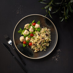 couscous with mushrooms and meatballs on a dark plate, top view