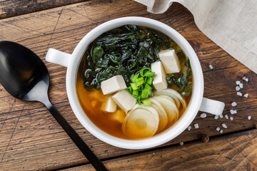 Japanese miso soup in a white bowl on the table. Horizontal view from above