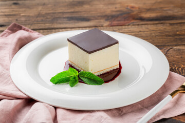 cake with souffle Bird's milk, biscuit, mousse and dark chocolate on a white plate