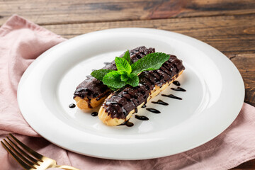 Eclairs with chocolate topping on serving plate