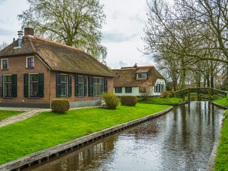 Thatched roof houses and lush garden on canal in the Dutch village of Giethoorn, Netherlands