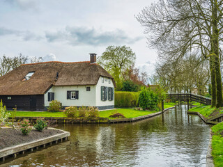 Fototapeta na wymiar Thatched roof houses on canal in the fairy tale village Giethoorn, Netherlands