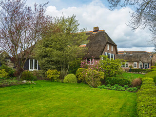 Fototapeta na wymiar Thatched roof houses and lush green gardens in the Dutch village of Giethoorn, Netherlands