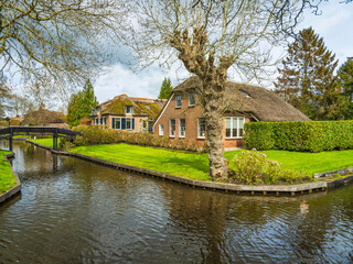 Fototapeta na wymiar Typical Giethoorn thatched roof houses on canal in the fairy tale village, Netherlands