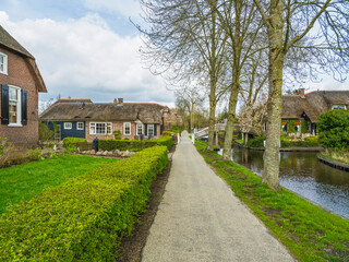 Street walkway and canal with thatched roof houses in the Dutch village of Giethoorn, Netherlands