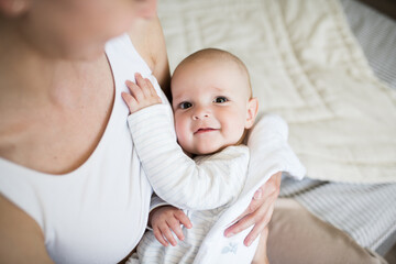 The concept of motherhood, care and love. happy caring young mother with a happy smile holds her adorable little son 6 months old in her arms, enjoying the sweet moments of happiness. 