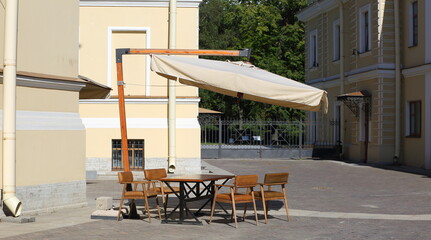 Table with chairs and awning in the courtyard of a residential building, Sadovaya Street, St....