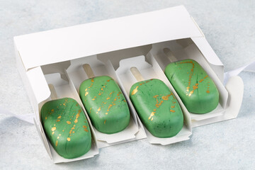 Greeen cake pops, popsicles in white box. Sweet concept. White background.