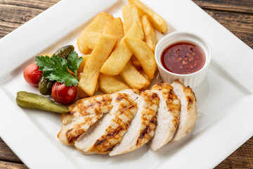 grilled chicken breast with baked potatoes on a white plate.